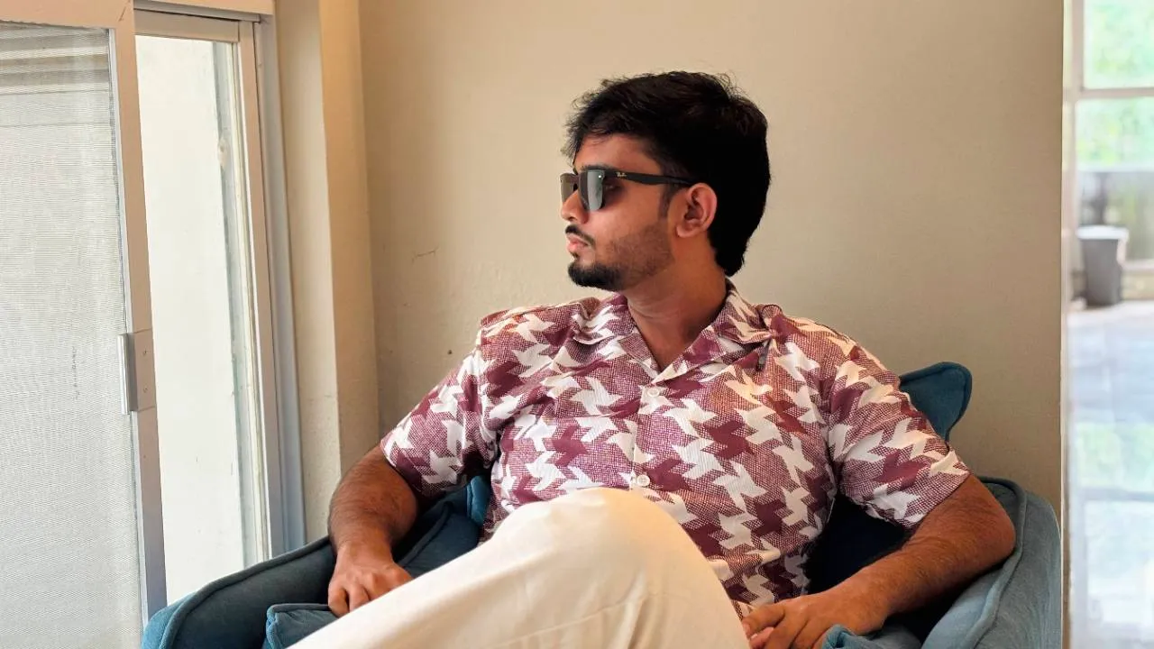 Tanzil Ahmed relaxing in a blue armchair by a window.